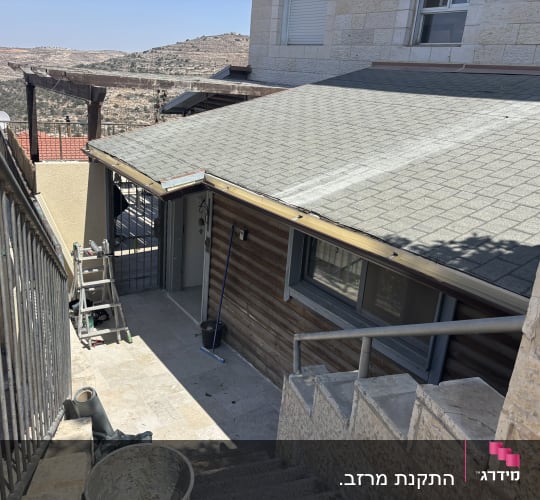 גג רעפים עם סולם וכלי עבודה ליד מדרגות חיצוניות